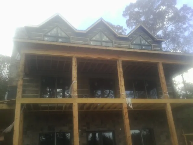 Dormers and porch framing on a large log home under construction — Roof Coating work by our crew in Clarence