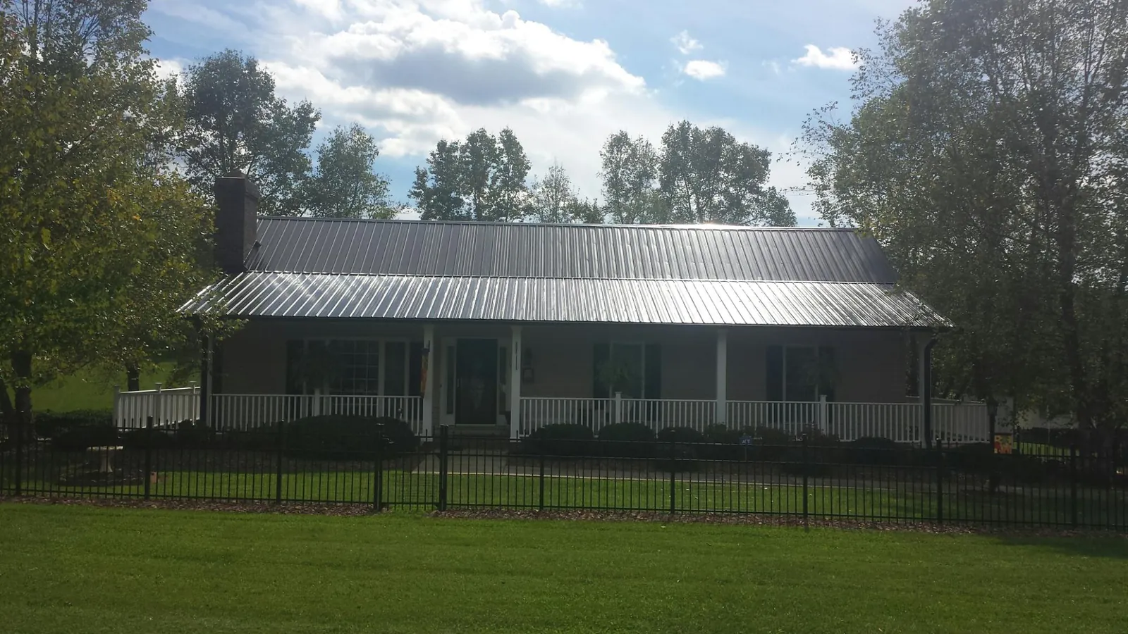 Gray metal roof on a brick ranch with a full width front porch — Gutter Guard Installation work by our crew in Clarence